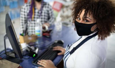 A masked grocery store worker rings up purchases